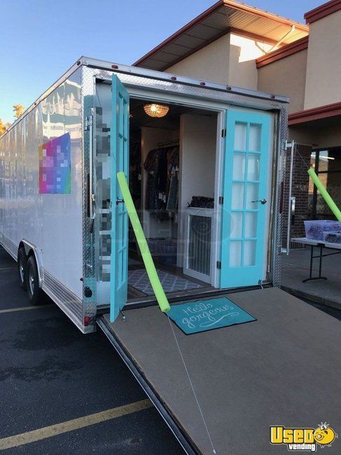 a large white trailer parked in front of a building with its doors open and the door ajar