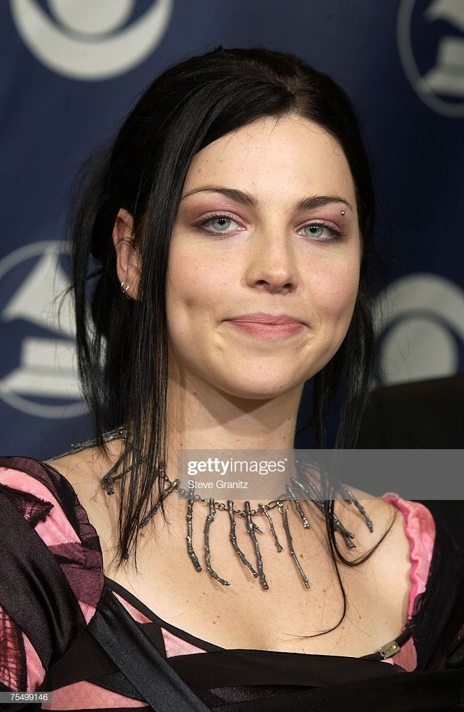 an image of a woman with black hair and piercings on her neck posing for the camera