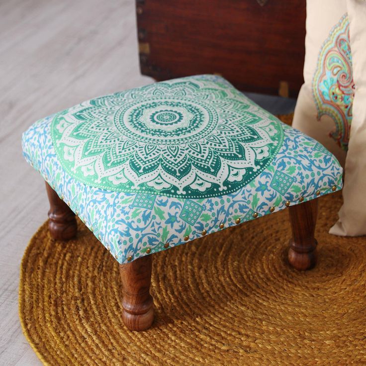 a blue and green ottoman sitting on top of a rug next to a wooden trunk