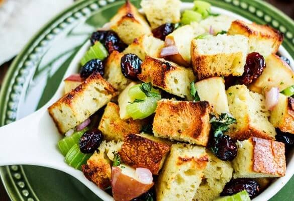 a white bowl filled with croutons and fruit on top of a green plate