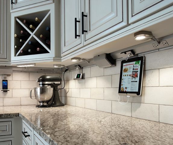 a kitchen with marble counter tops and white cabinets, an ipad on the counter top