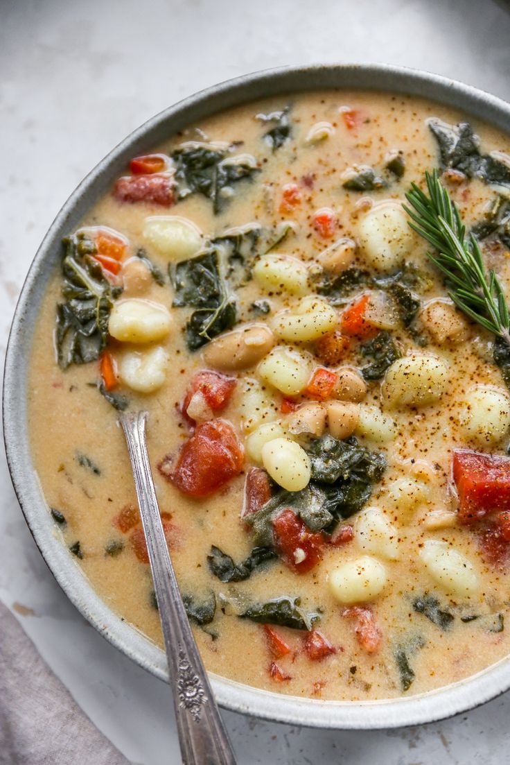 a bowl of soup with potatoes, spinach and tomatoes