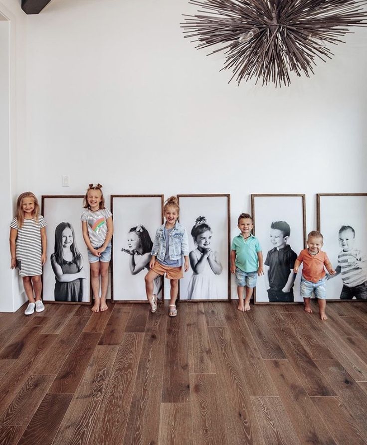 several children are standing in front of pictures on the wall