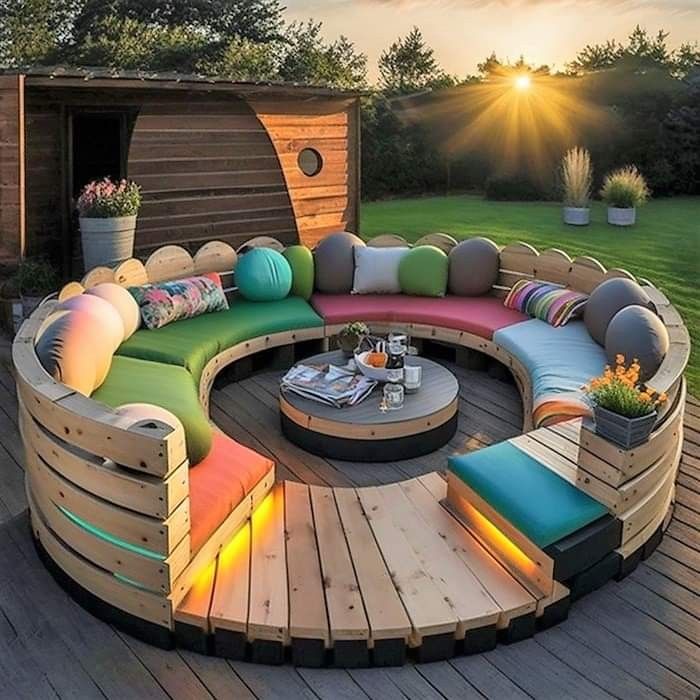 a circular couch sitting on top of a wooden deck next to a green grass covered field