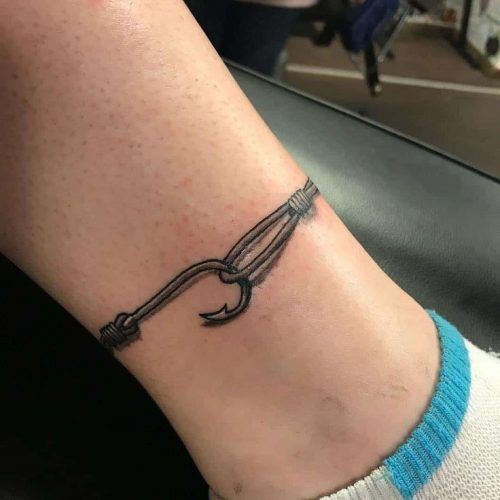 a person with a tattoo on their foot has a chain attached to the ankle that is holding a fishing hook