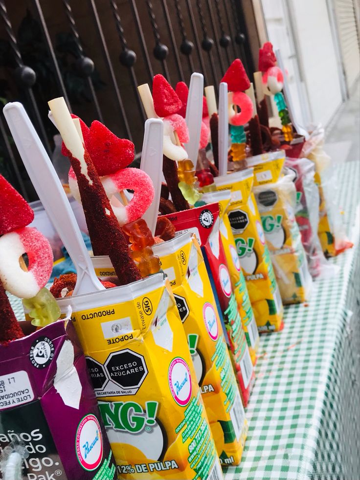 several ice creams lined up on a table with spoons sticking out of them