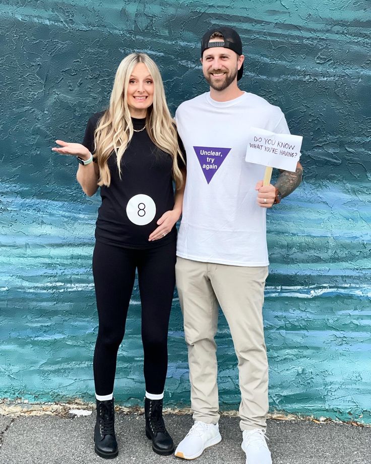 a man and woman standing next to each other in front of a wall holding signs