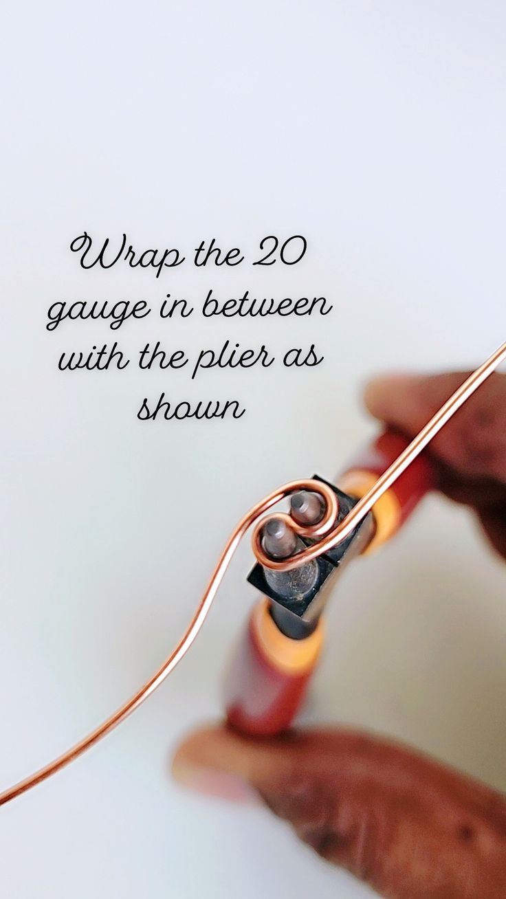 a person holding a piece of wire with the words wrap the 20 gauge in between with the plier as shown