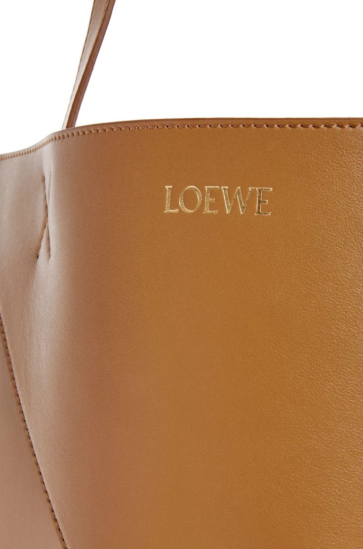 [vc_row][vc_column width=”1/3″][vc_column_text text_larger=”no”] LOEWE LOEWE XL Puzzle Fold Tote in shiny calfskin The Puzzle Fold Tote takes the iconic bag’s signature geometric lines and reimagines them in graphic and architectural panels that allow the bag to fold completely flat, making it the perfect travel companion. Soft, lightweight and inventively crafted, it is finished with discreet LOEWE branding. This XL version is crafted in shiny calfskin. LOEWE XL Puzzle F Designer Calf Leather Bags With Logo, Modern Rectangular Bag With Engraved Logo, Modern Top Handle Bags With Engraved Logo, Modern Rectangular Bags With Engraved Logo, Rectangular Bags With Engraved Logo, Chic Bag With Engraved Logo, Glossy Leather Tote Bag, Designer Leather Bag With Glossy Finish, Elegant Workwear Bags With Logo