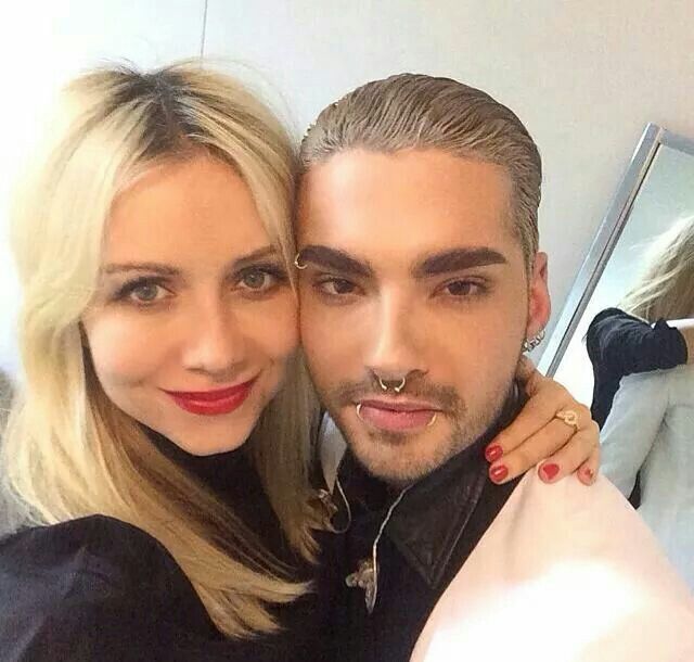 a man and woman posing for a photo in front of a mirror with their arms around each other