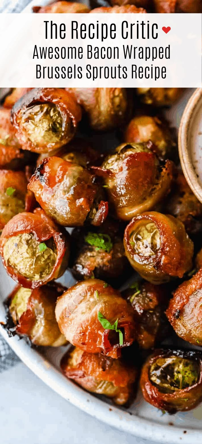 bacon wrapped brussel sprouts on a white plate with a small bowl of sauce