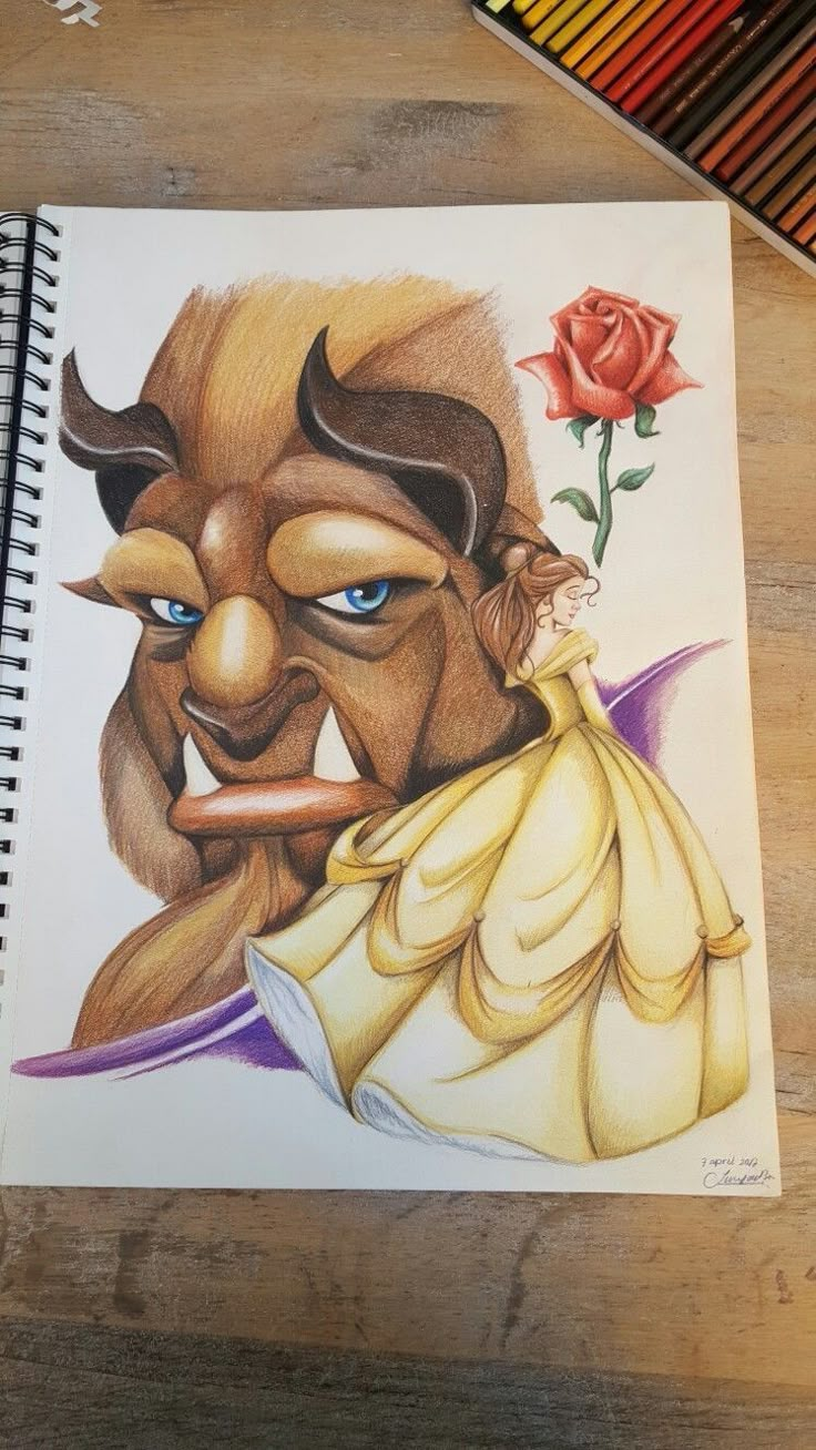 a drawing of beauty and the beast on a table with colored pencils next to it