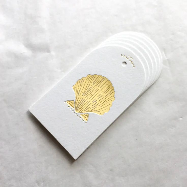 a white card with gold foiled seashells on it