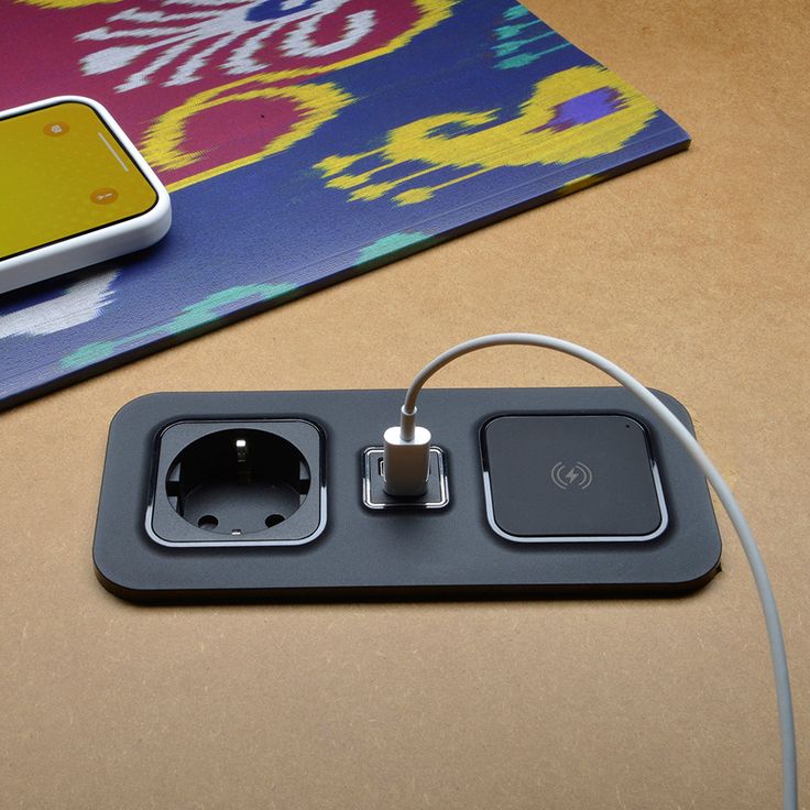 an electronic device is plugged in to a charger on a table next to a phone