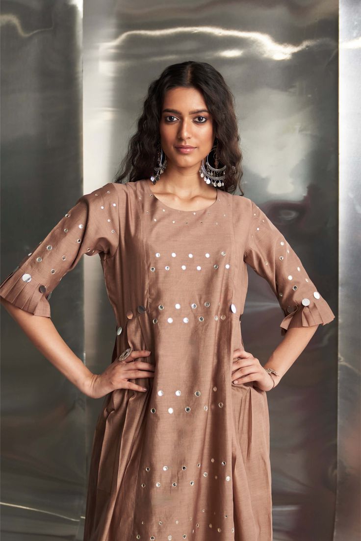 This Chanderi kurta in a beautiful ginger hue features mirror work on the front panel and sleeves, with stylish pleated sleeves adding flair. Paired with a Chanderi dupatta embroidered with mirror work along the borders, and wide-flare cotton palazzos highlighted with mirrors, this ensemble ensures a stylish and coordinated look. The bottom is elasticated with a drawstring for comfort. Chanderi Dupatta, Chanderi Kurta, Jacket Cape, Drape Saree, Designer Jumpsuits, Pleated Sleeves, Sharara Set, Skirt Co Ord, Mirror Work