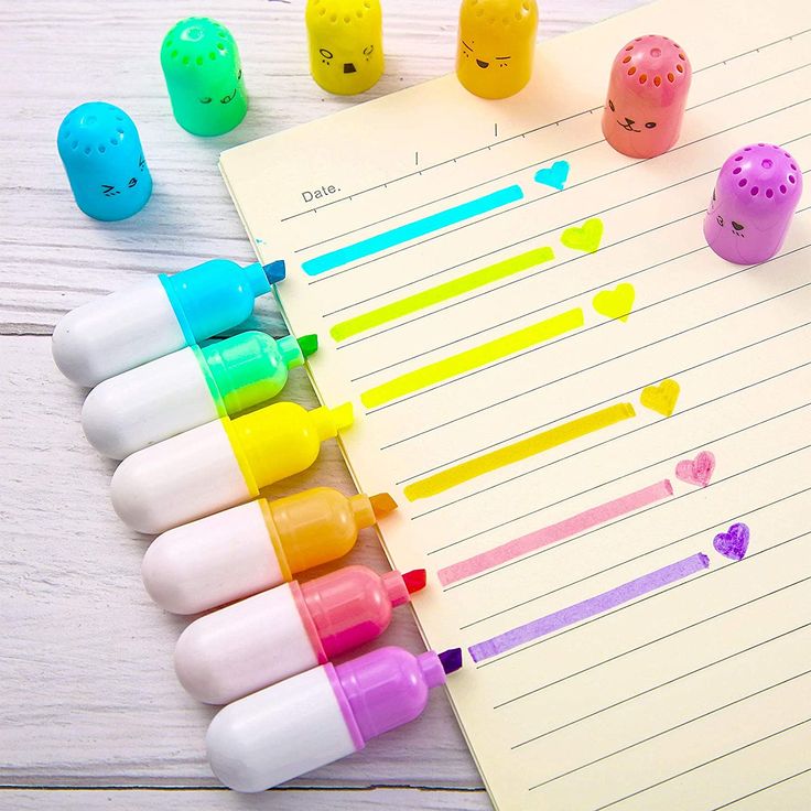 several different colored pens sitting on top of a notepad