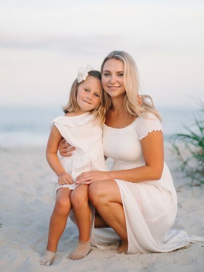 a mother and daughter sitting on the beach