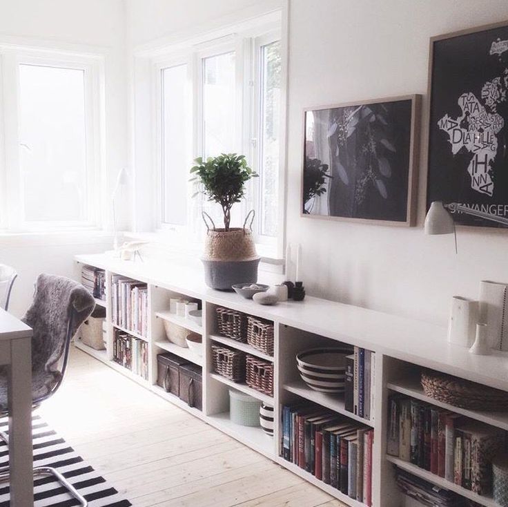 a living room filled with lots of furniture and bookshelves next to a window