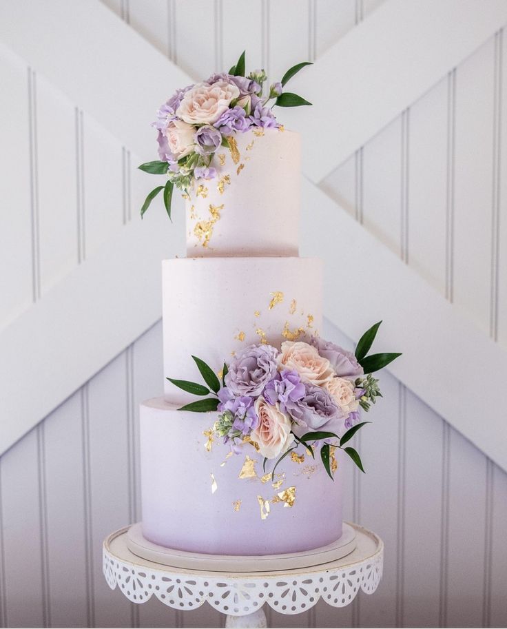 a three tiered cake with purple flowers on top