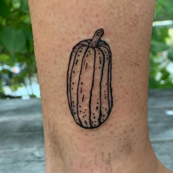 a small black and white pumpkin tattoo on the ankle