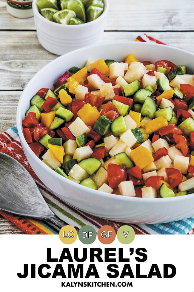 a white bowl filled with sliced vegetables on top of a wooden table next to spoons