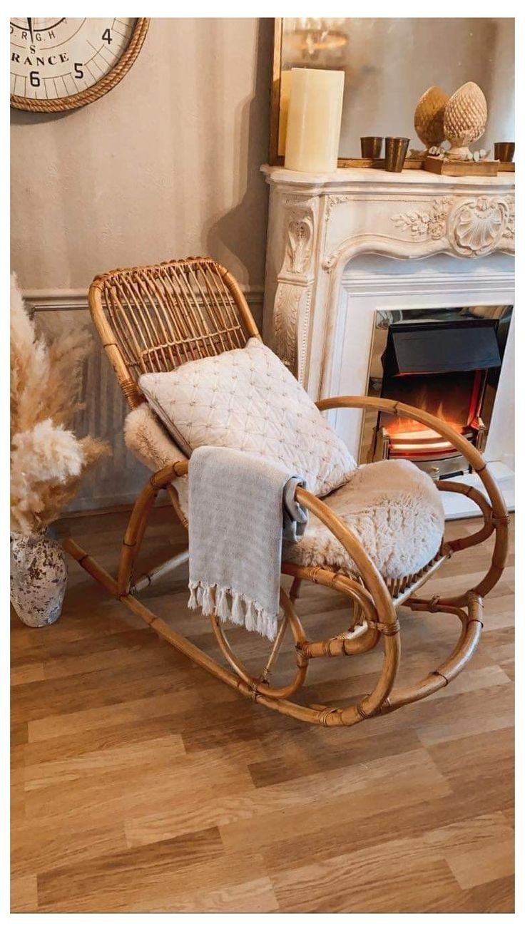 a rocking chair with a blanket on it next to a fireplace