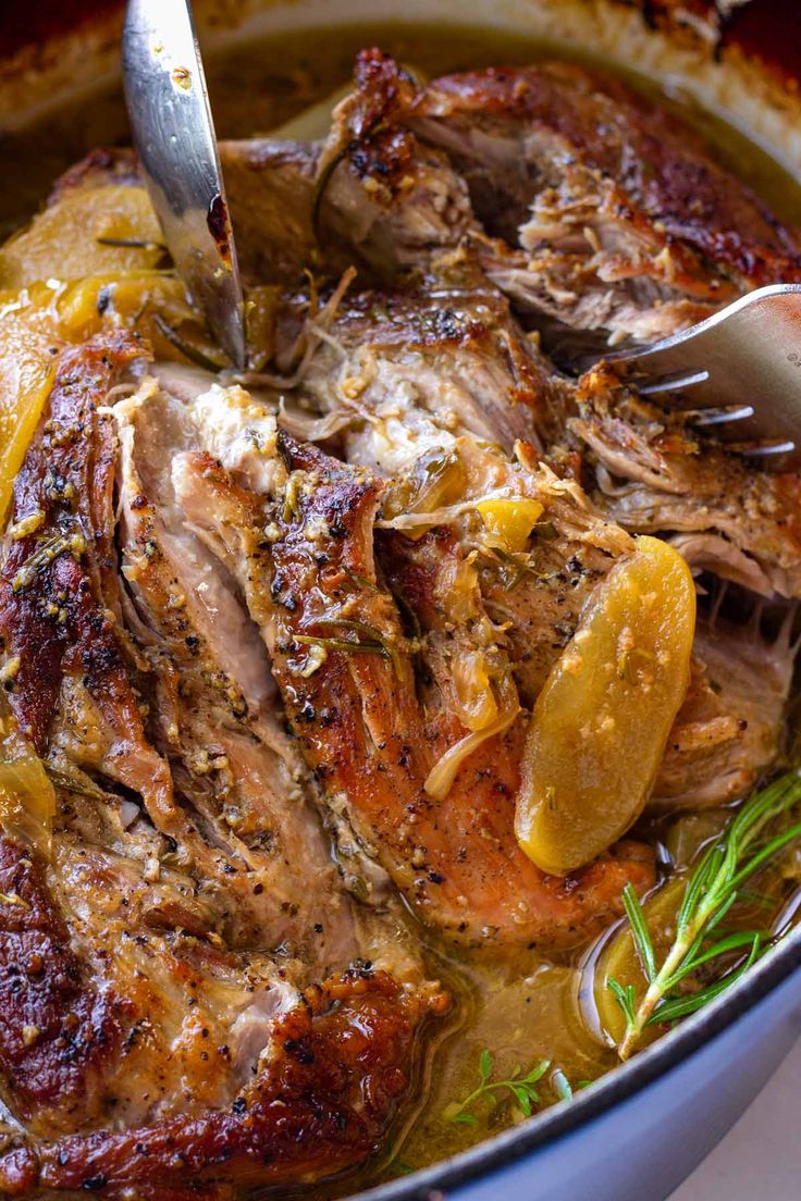 a large pot filled with meat and vegetables on top of a white tablecloth next to a fork