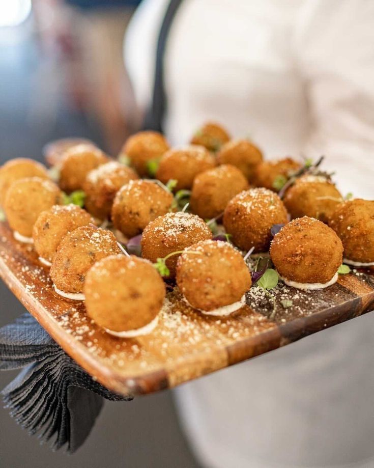 a person holding a wooden tray with food on it and garnished with sprinkles