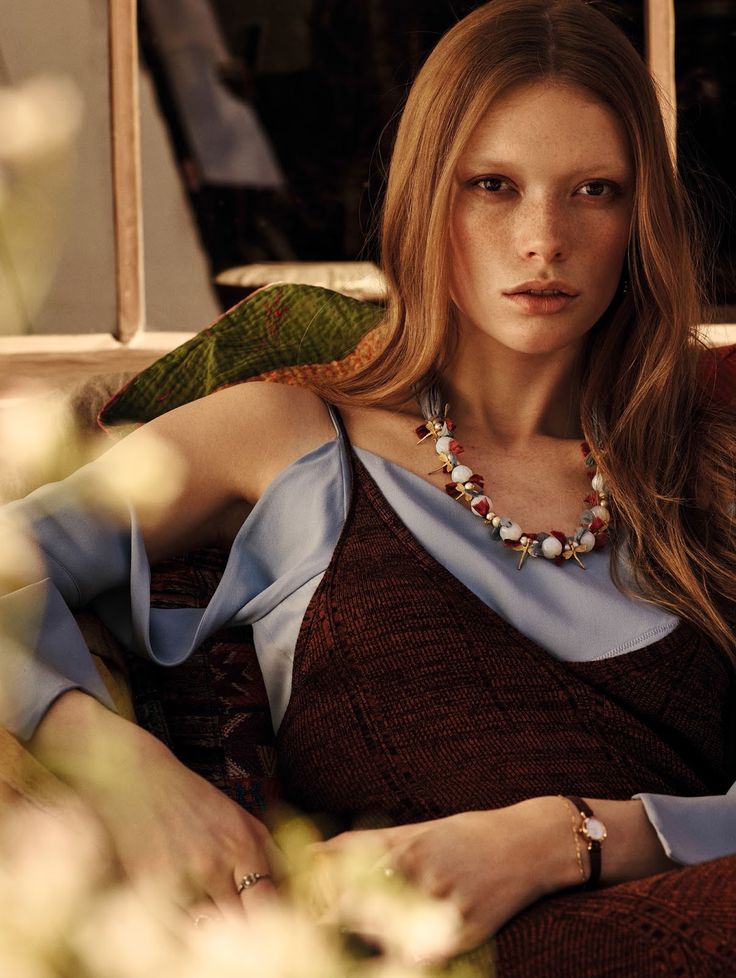 a woman sitting in a chair wearing a necklace