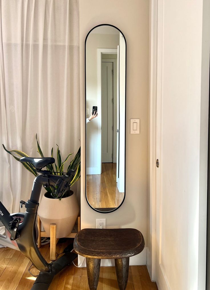 a bike is parked in front of a mirror and a stool with a plant on it