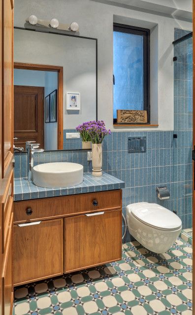 a bathroom with blue tile and wooden cabinets, toilet and sink in the center area