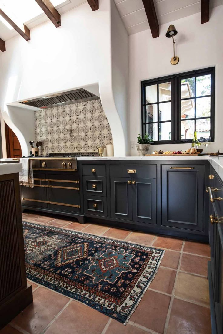 a large kitchen with black cabinets and an area rug on the floor in front of it