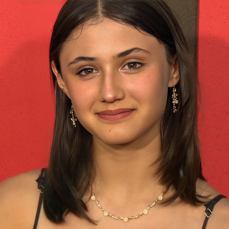 a close up of a person wearing a necklace and earring with an expression on her face