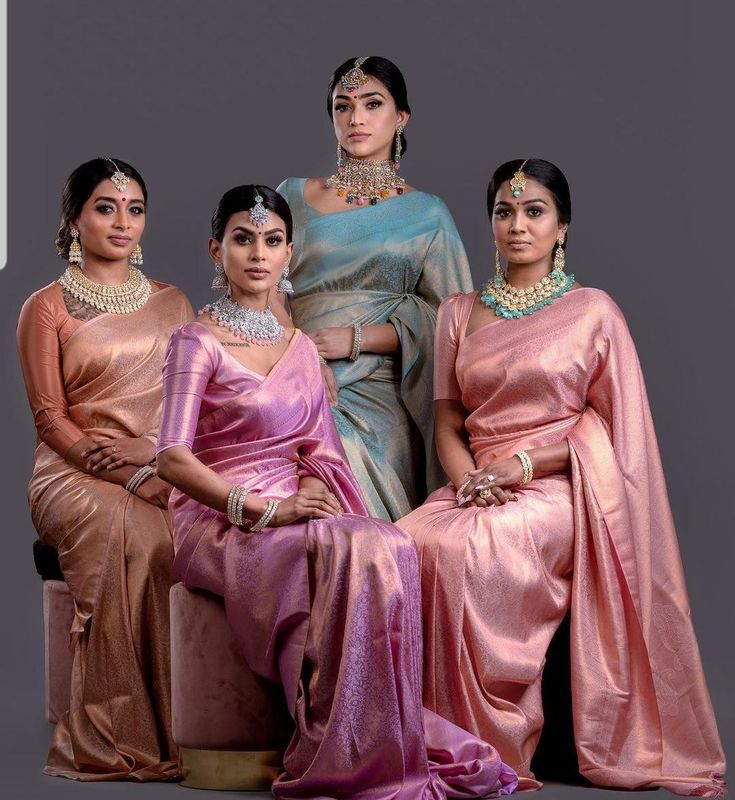 three women in sari sitting next to each other and posing for the camera with their hands on their hips