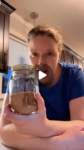 a woman holding a jar filled with brown stuff in her hands and making a face