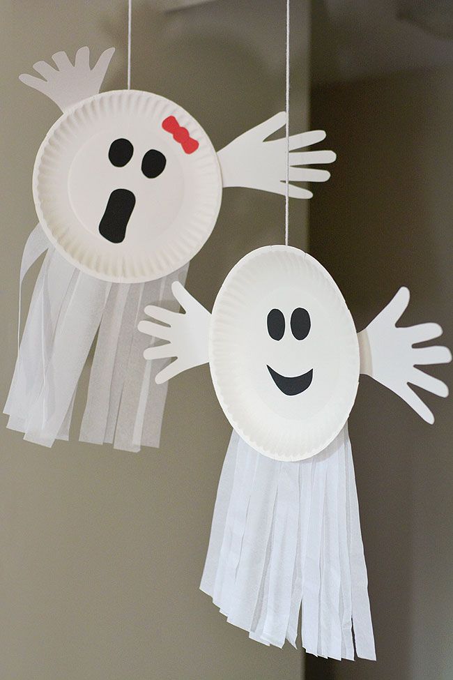 two paper plates with ghost faces hanging from strings