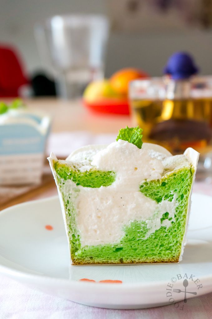 a green cupcake with white frosting on a plate