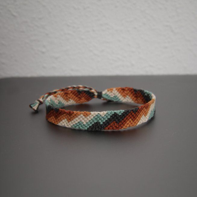 two bracelets sitting on top of a table next to a white and brown wall