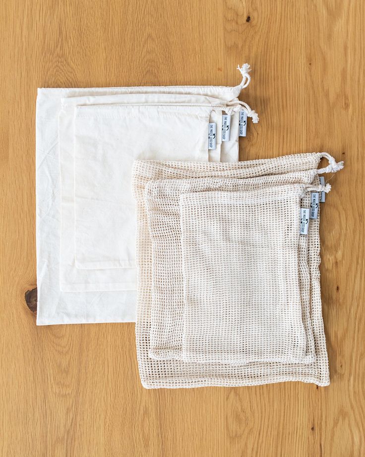 three white mesh bags sitting on top of a wooden floor