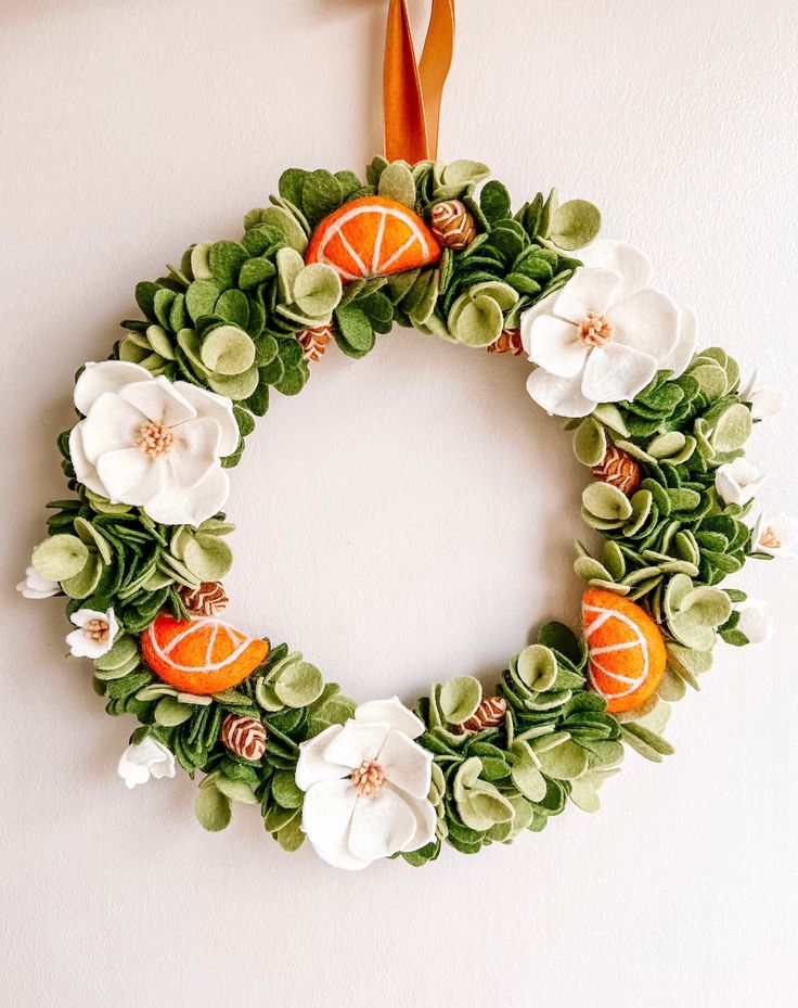 an orange and white flower wreath hangs on the wall