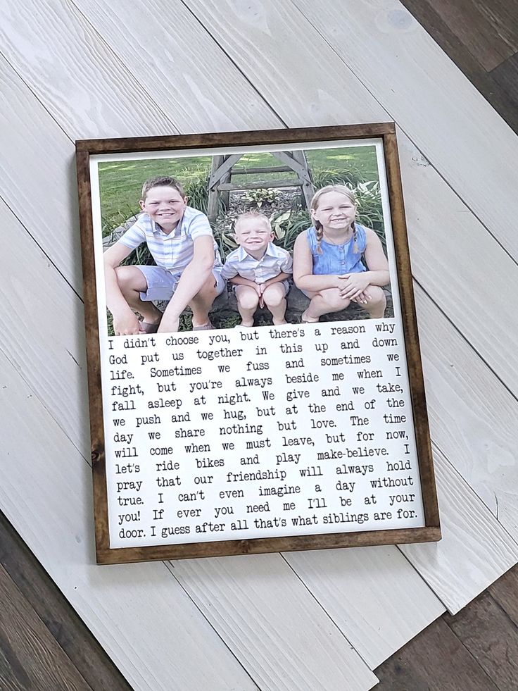 an old photo frame with two young boys sitting on top of it, in front of a wood floor