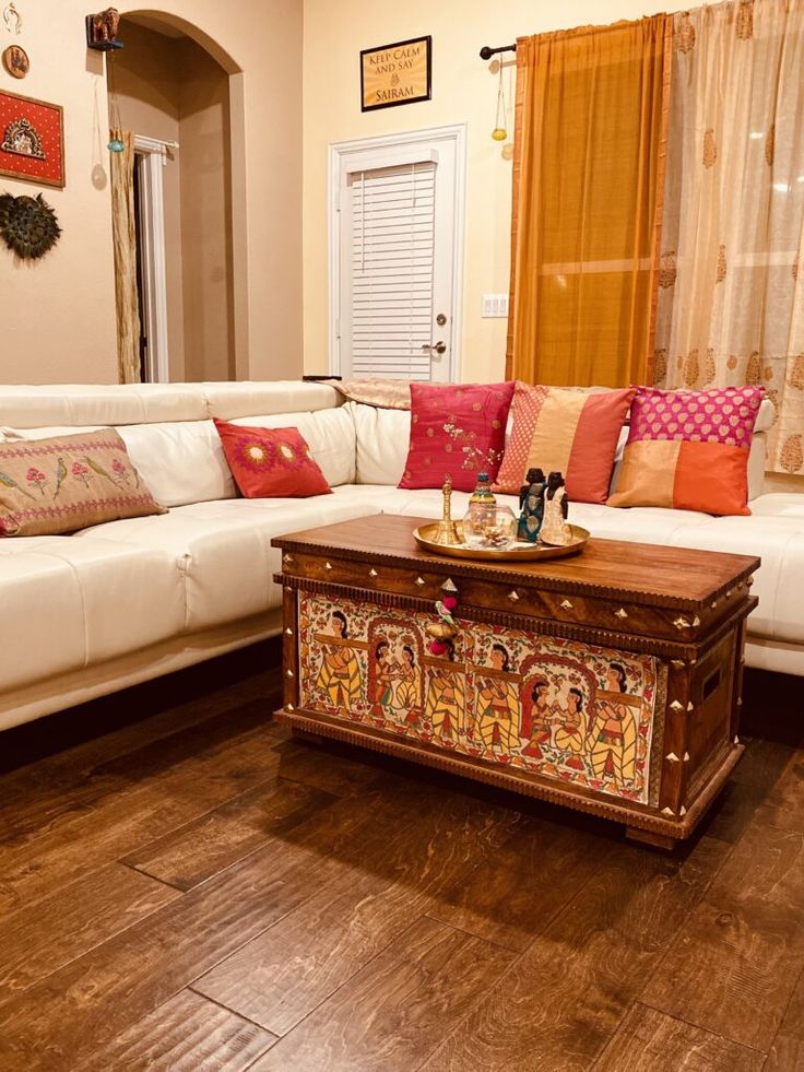 a living room with white couches and colorful pillows on top of the coffee table