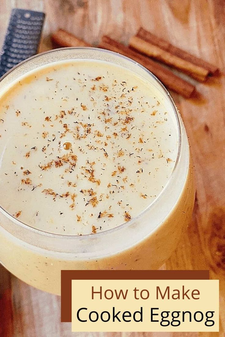 a close up of a drink on a wooden table with cinnamon sticks in the background