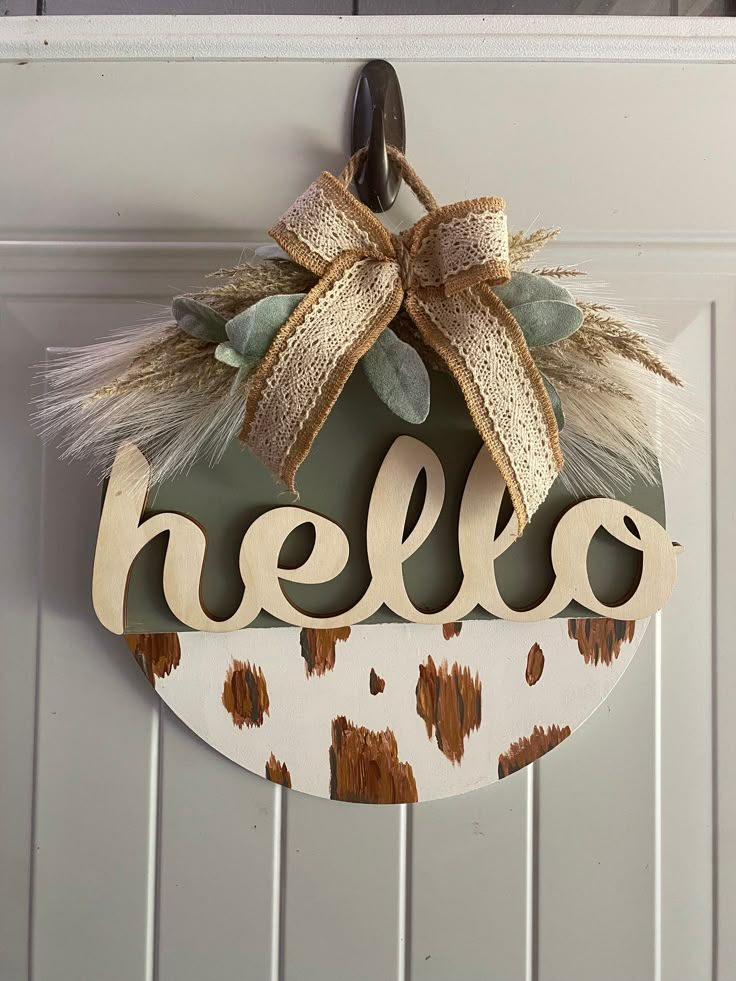 a door hanger with the word hello on it and a bow hanging from it