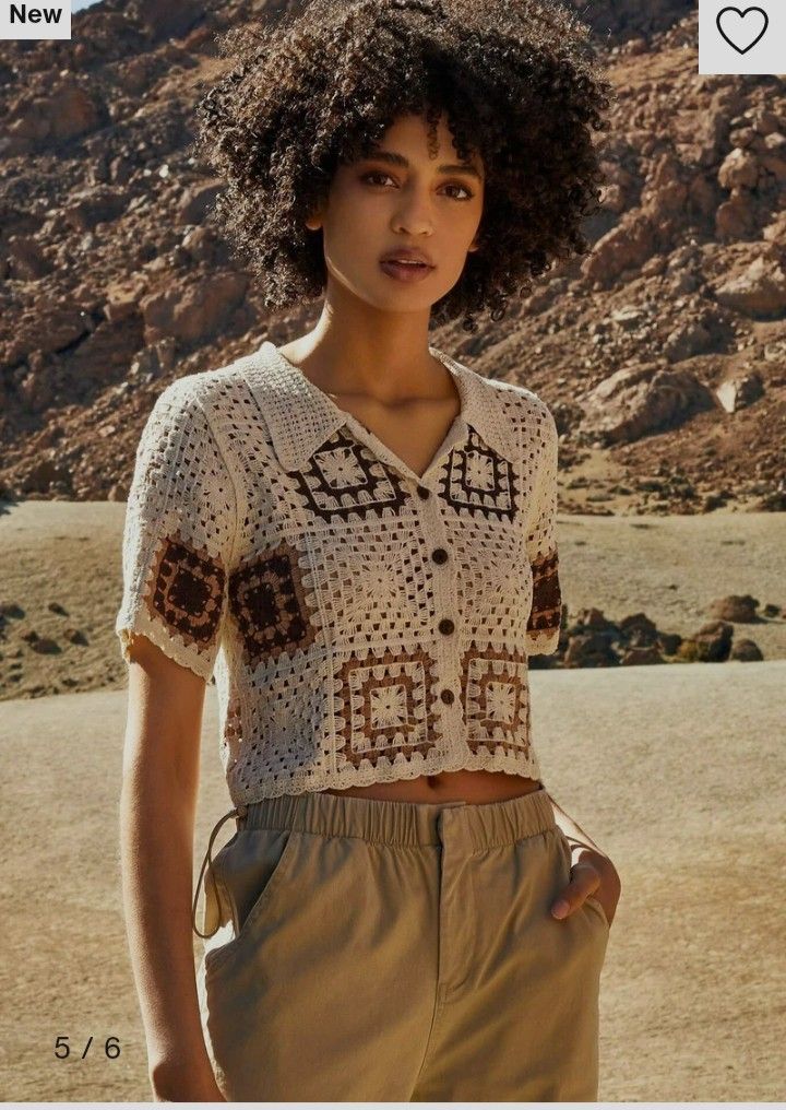 a woman standing in the desert wearing a white shirt and tan pants with an afro hairstyle