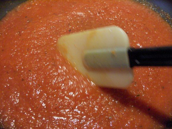 a bowl filled with sauce and cheese being stirred by a whisk on top