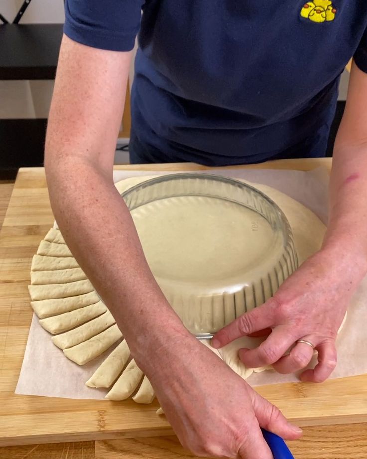 a person cutting dough on top of a wooden table