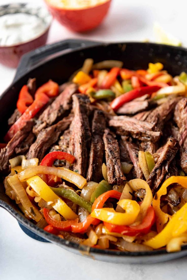 steak and bell peppers in a skillet ready to be cooked on the stove top