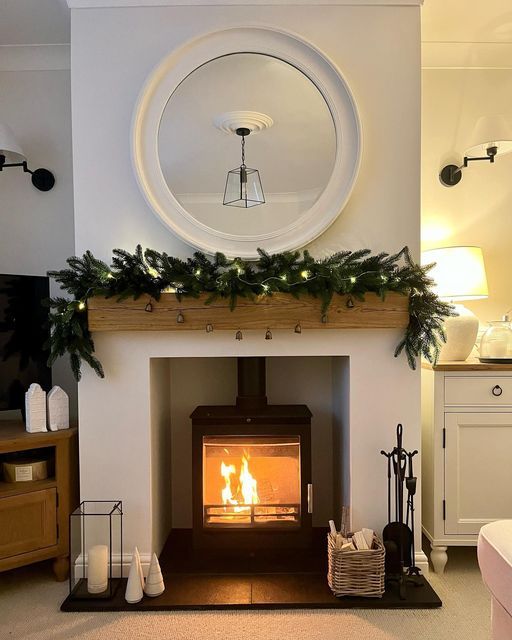 a living room with a fire place in the center and christmas decorations on the mantle