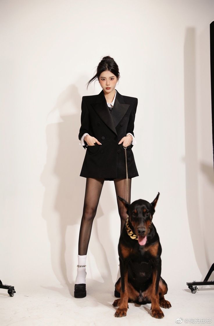 a woman standing next to a dog in front of a white wall wearing tights